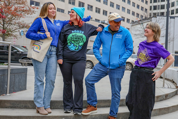 Four people stand on a short set of stairs, each wearing or holding AGU merchandise