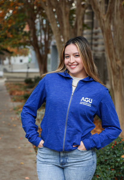 A woman wears a blue lightweight hoodie with the AGU logo printed in white