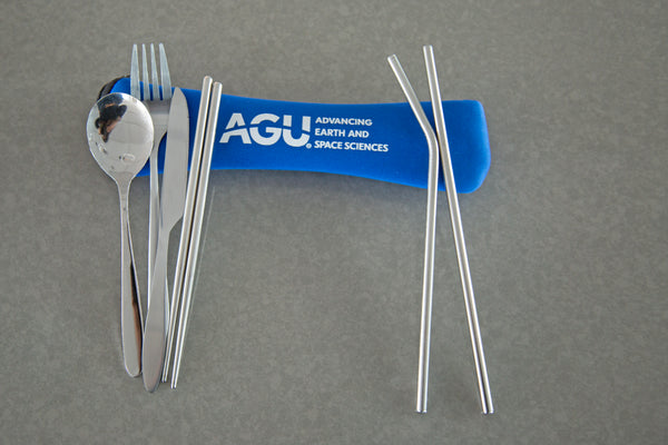 A set of stainless steel flatware is displayed next to a blue pouch with the AGU logo printed in white.