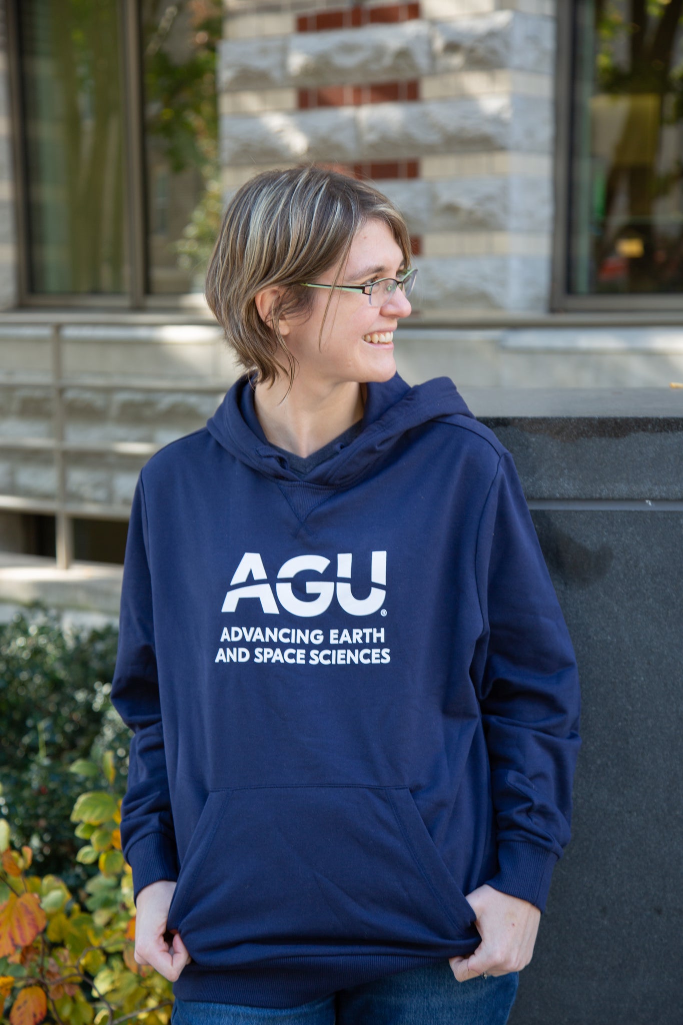 Woman wears a navy blue hoodie with the AGU logo printed in white