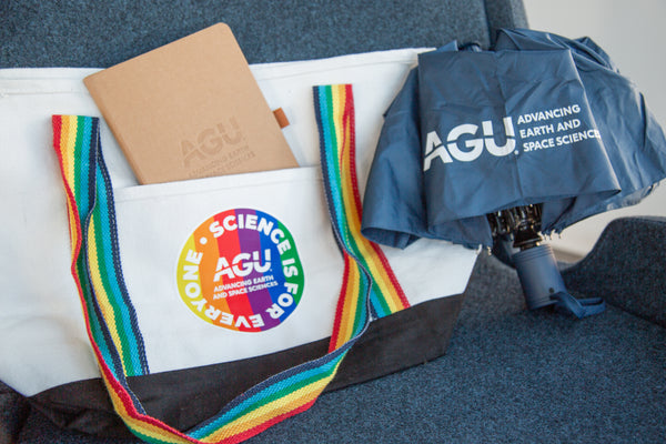 Folded umbrella with AGU logo pictured beside an AGU tote bag